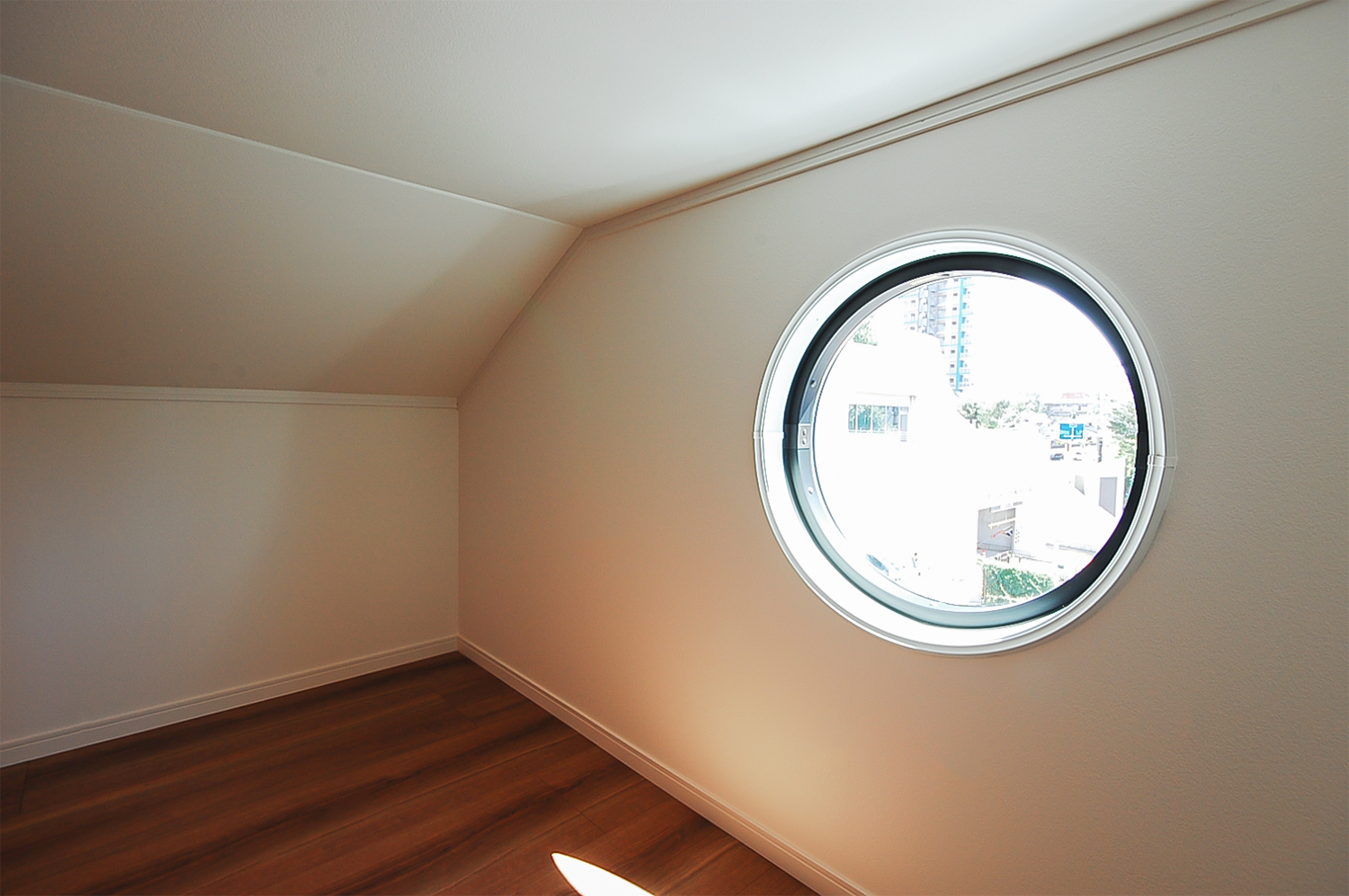 丸窓を設えた固定階段式の小屋裏収納。収納スペースとして活用しながらも遊び心溢れる空間に